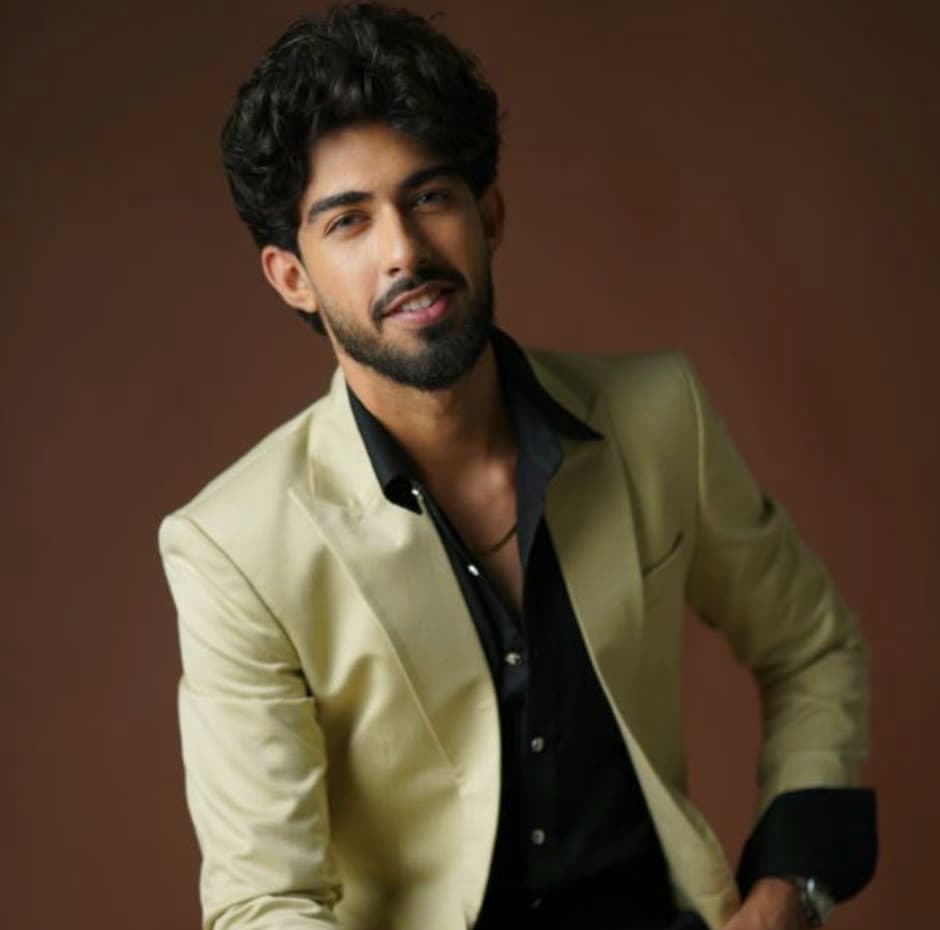 Portrait of Harsh Punjabi in a cream jacket against a warm brown ground